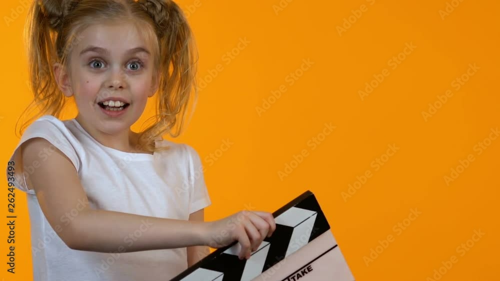 Funny little kid using clapboard and smiling on camera, junior acting school Funny little kid using clapboard and smiling on camera, junior acting school