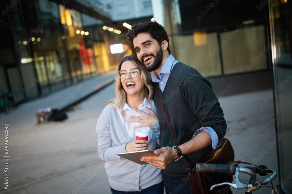 Beautiful young couple walking down the street with tablet
