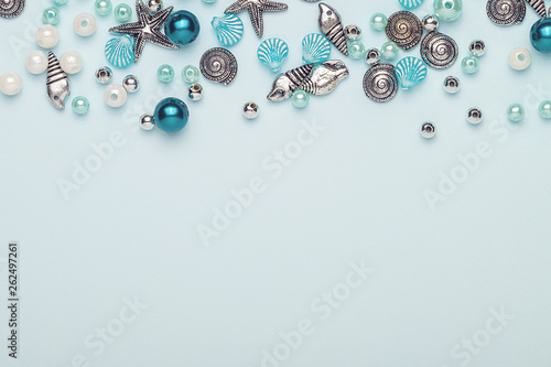 Glass, plastic, metal beads. Beads in the form of shells. Marine theme. On a blue background. The view from the top.