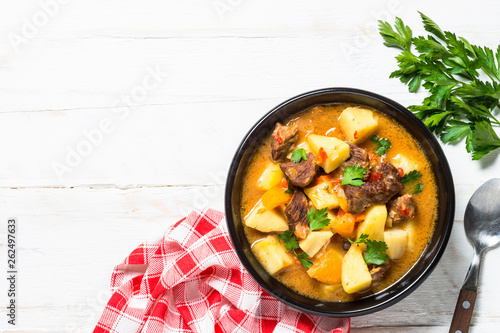 Goulash with meat and vegetables on white wooden table. photo