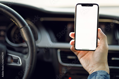 Young business man with phone in car. Man holding smartphone with blank screen .