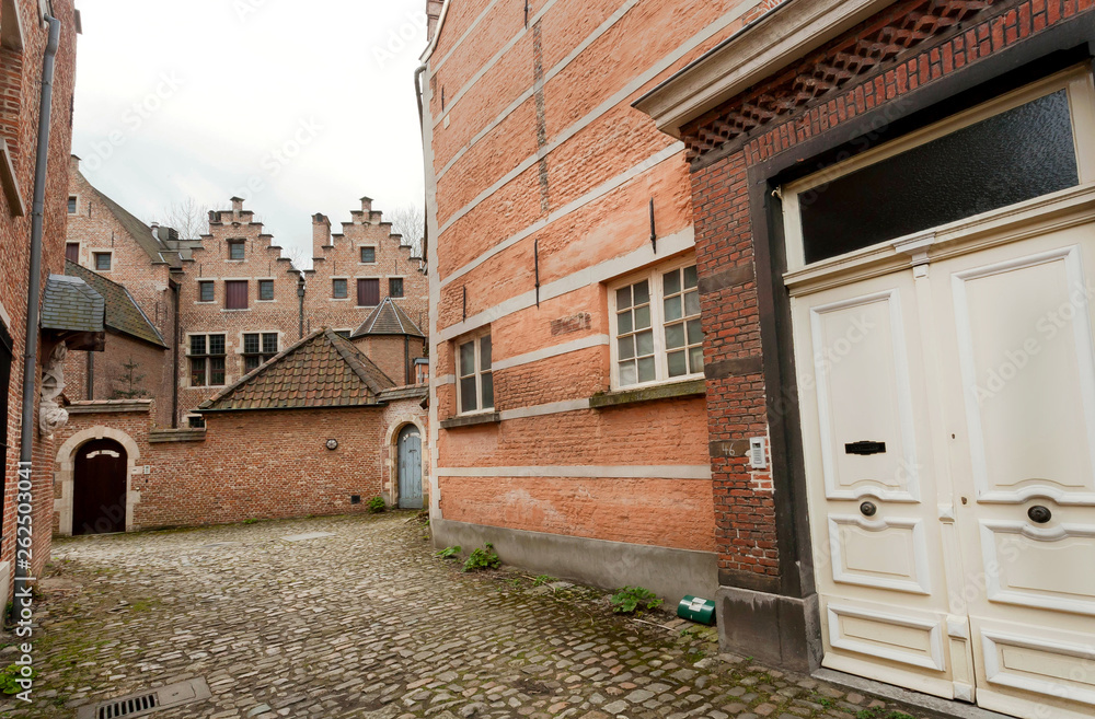 Closed door of brick wall home of historical Beguinage, 13th century complex houses for beguines women