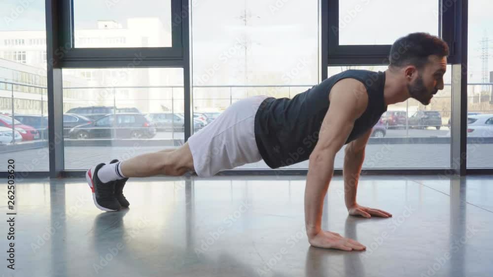 Sportsman in sneakers doing push ups in gym Sportsman in sneakers doing push ups in gym