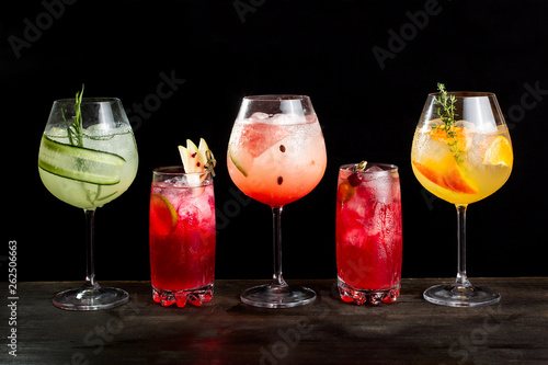 Five alcoholic cocktails with orange slices, ice, watermelon slices and cucumbers. photo