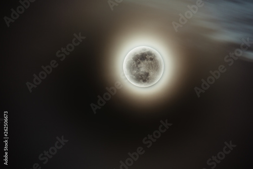 Full moon with yellow glow of sun behind it during eclipse