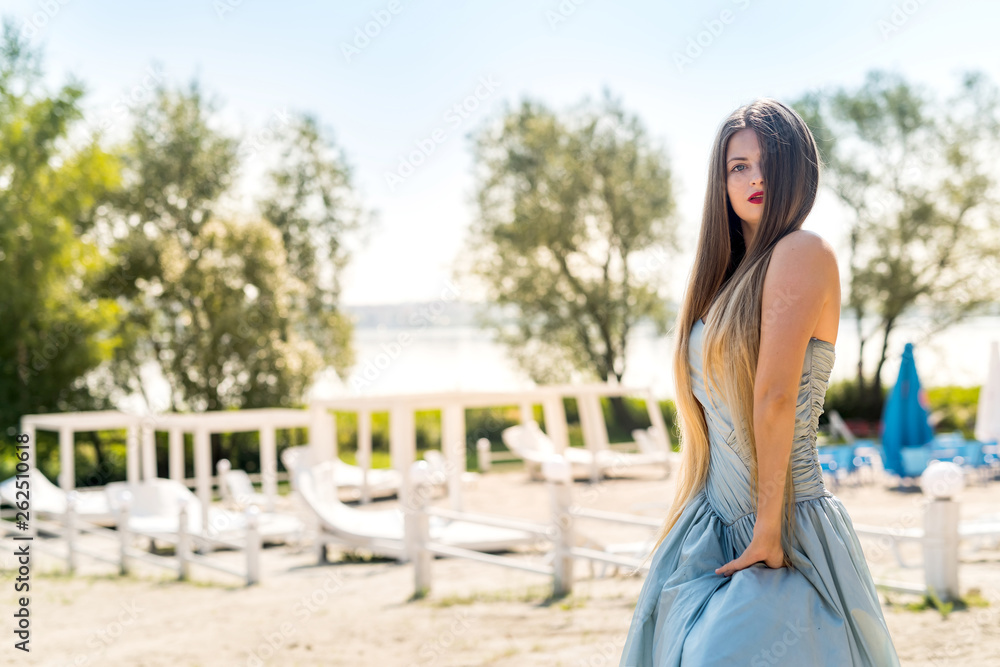 Beautiful woman wearing elegant dress posing on beach
