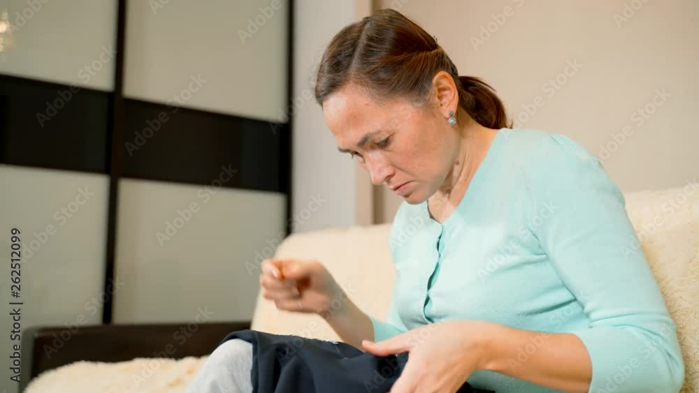 Woman sews sequins on the dress. Needle and thread in girl's hands. Fashion concept. Freelance work at home. Creating of new clothes process. Hobby ideas.