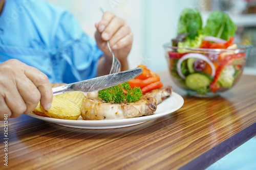 Asian senior or elderly old lady woman patient eating breakfast healthy food with hope and happy while sitting and hungry on bed in hospital.