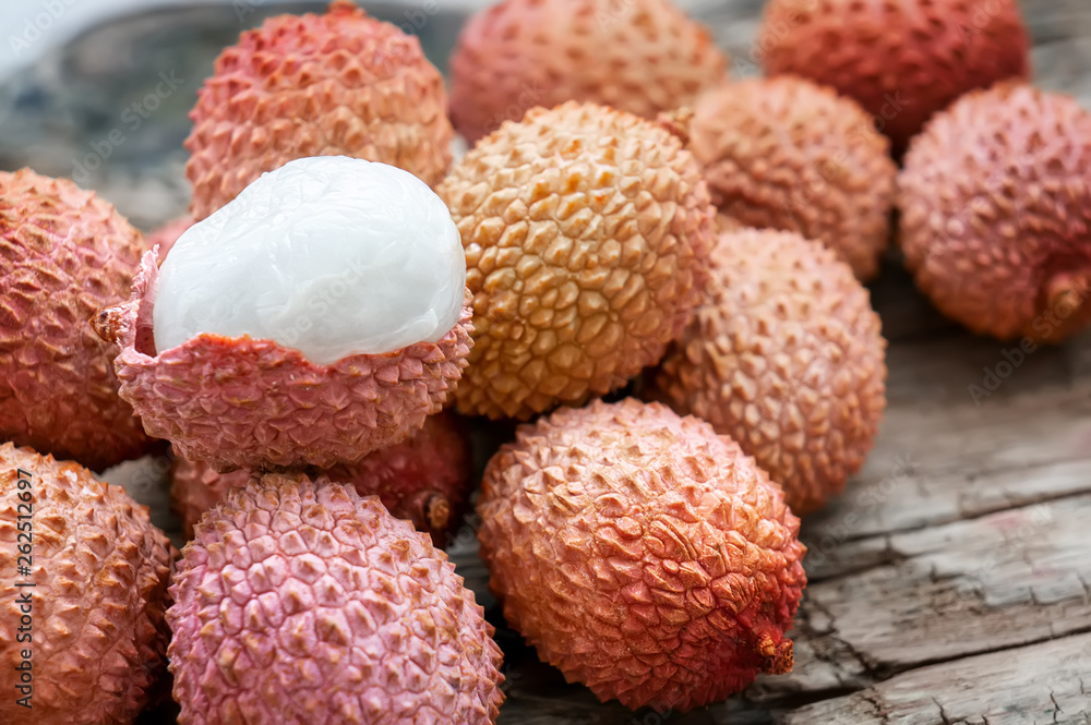 Fresh organic lychee fruit in a bowl on a rustic wooden background. Healthy vegan food concept. Close-up