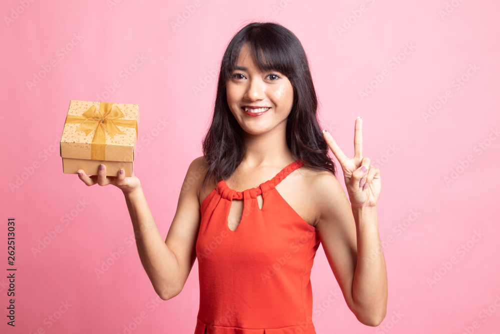 Young Asian woman show Victory sign with a gift box. Young Asian woman show Victory sign with a gift box.