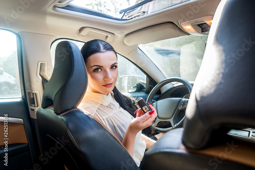 Woman sitting inside new car offering key © RomanR