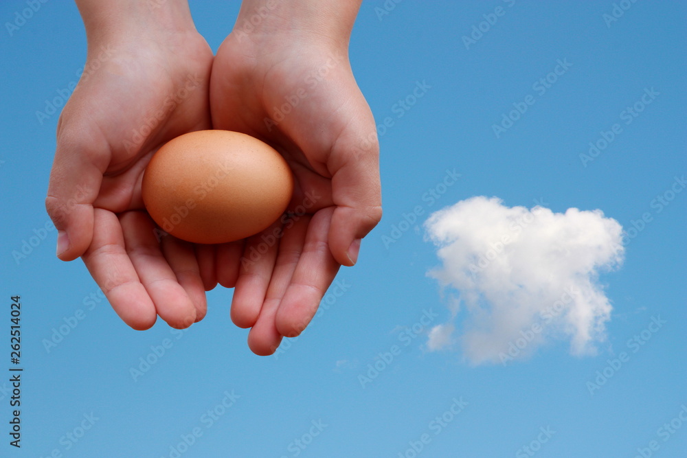 Egg in hands on blue sky background with cloud Egg in hands on blue sky background with cloud