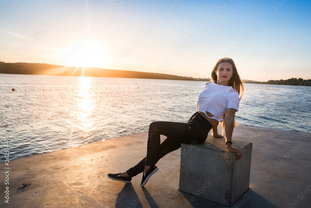 Woman posing at lakeshore sitting at cube