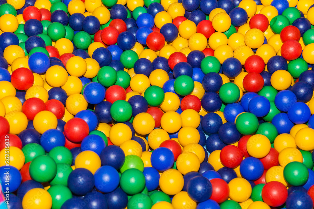 Top view colorful plastic balls in a dry pool. Plastic colorful balls for playing. Colorful plastic gum balls background in kid playroom or playground for children's holiday party concept Top view colorful plastic balls in a dry pool. Plastic colorful balls for playing. Colorful plastic gum balls background in kid playroom or playground for children's holiday party concept