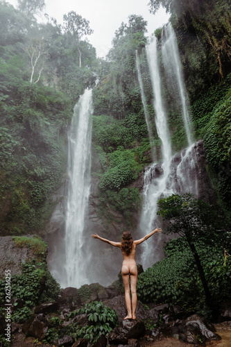 Unrecognizable Woman in bikini enjoying waterfall in jungle