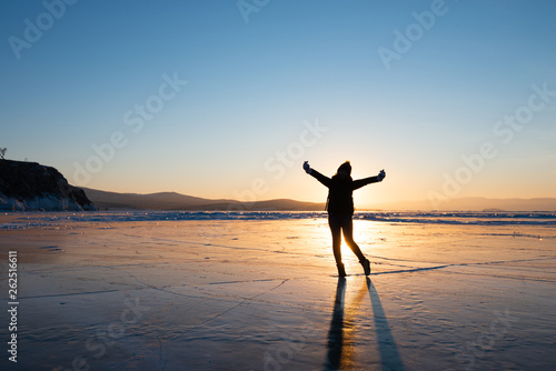 Silhouette photo of woman is walking and raise her hand on frozen lake at Baikal © magneticmcc