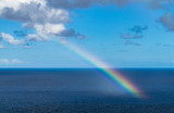 Rainbow in the Atlantic ocean, with blue sky and with clouds