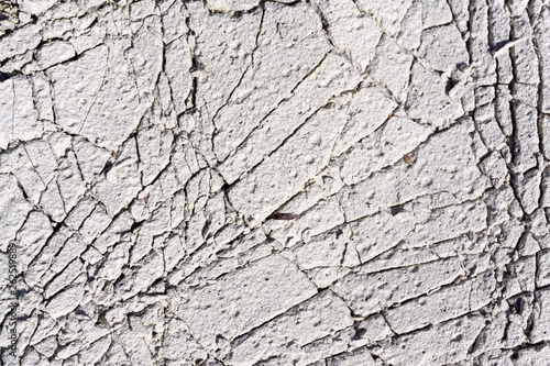 Cracked concrete texture background. Grey surface with cracks close up. A lot of pieces of splintered plaster. Abstract concept of split, dissent, disagreement, discord. Sunny day with .