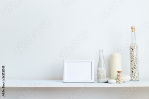 Shelf against white wall with decorative candle, glass and rocks. © MexChriss