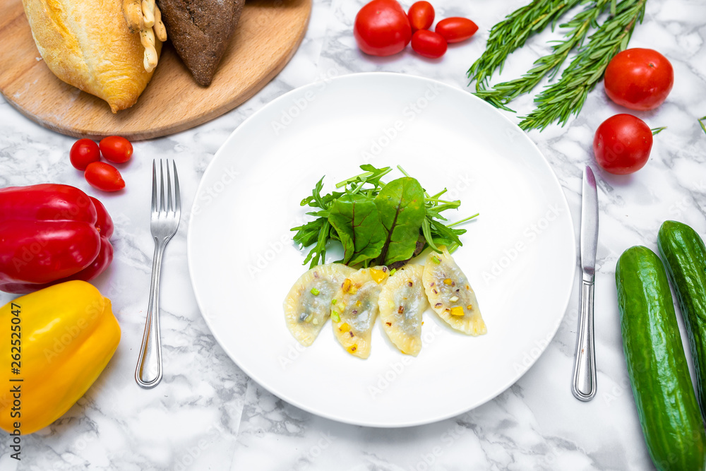Dumplings, filled with cabbage. vegetable dumplings. Dumplings with potatoes in plate on white background. Ingredients for dumplings with cabbage, potatoes, tomato, cucumber, lettuce, pepper. Top vie Dumplings, filled with cabbage. vegetable dumplings. Dumplings with potatoes in plate on white background. Ingredients for dumplings with cabbage, potatoes, tomato, cucumber, lettuce, pepper. Top vie