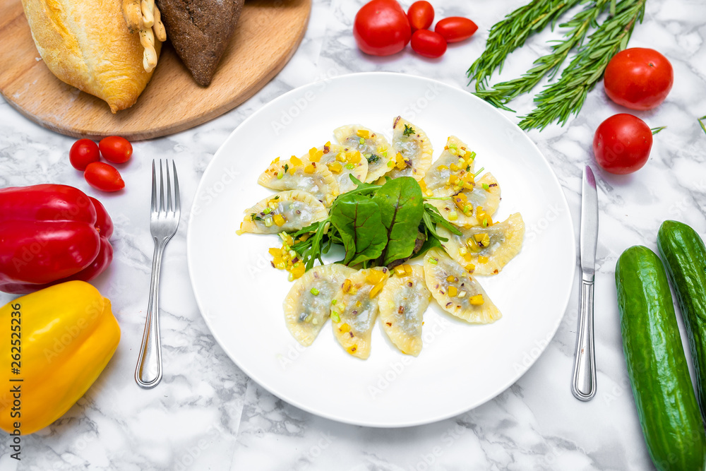 Dumplings, filled with cabbage. vegetable dumplings. Dumplings with potatoes in plate on white background. Ingredients for dumplings with cabbage, potatoes, tomato, cucumber, lettuce, pepper. Top vie