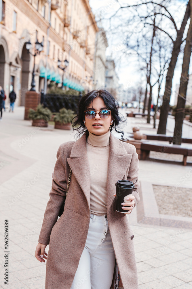 Fototapeta premium Beautiful woman holding paper coffee cup and enjoying the walk in the city