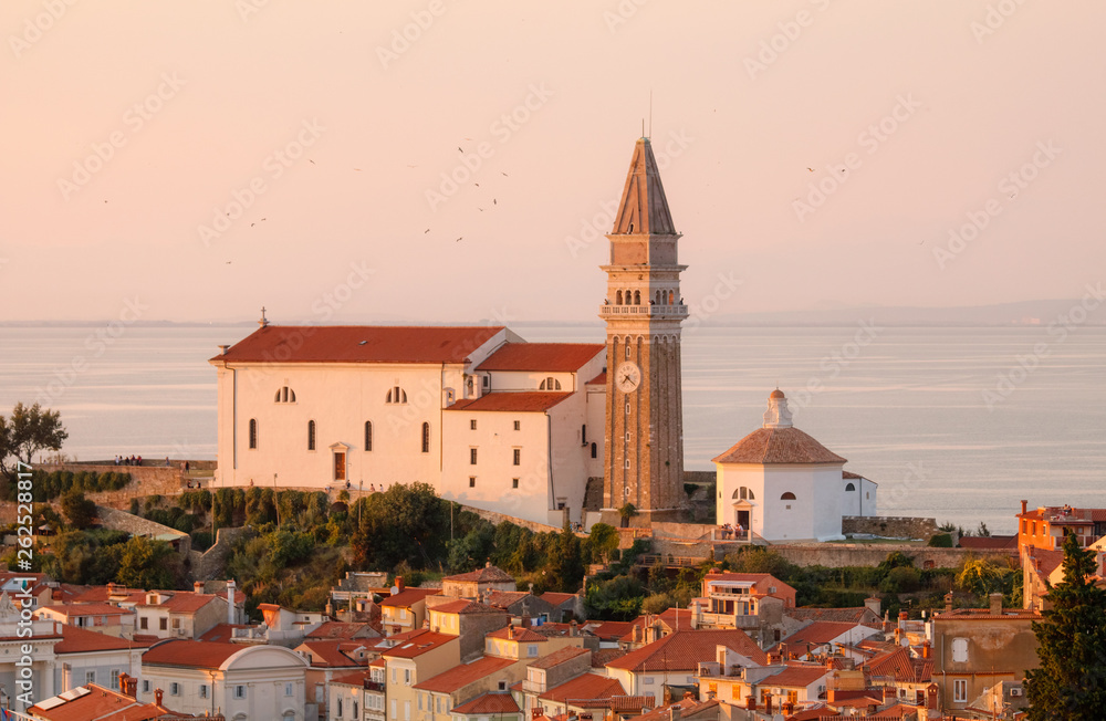 The church in Piran in Slovenia at dusk with a red sunset over the Adriatic