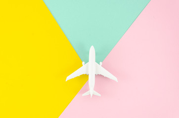 Flat lay white toy plane on yellow and light pink pop background