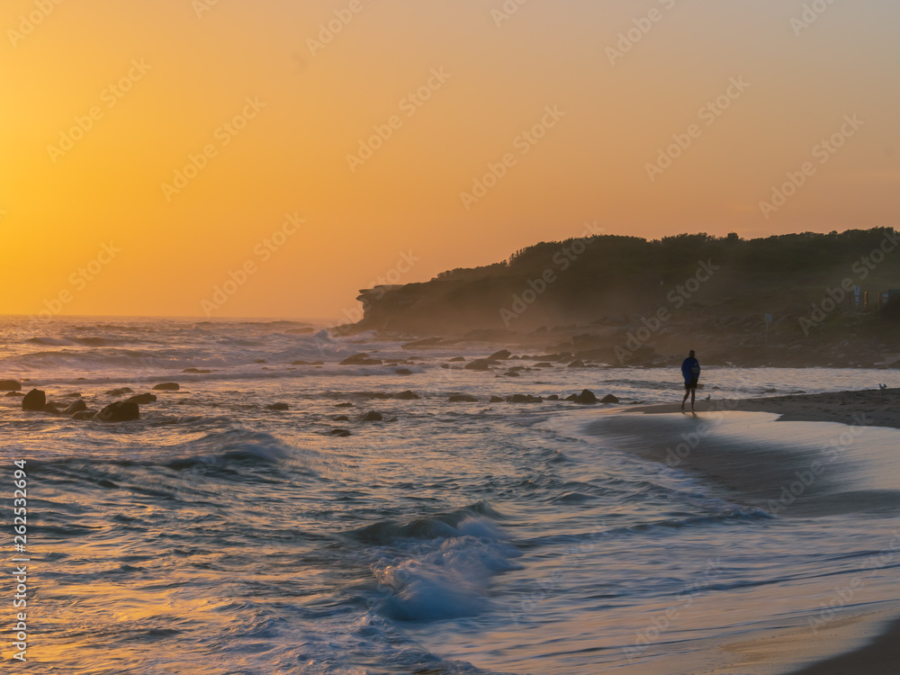 man walking on the beach at sunrise