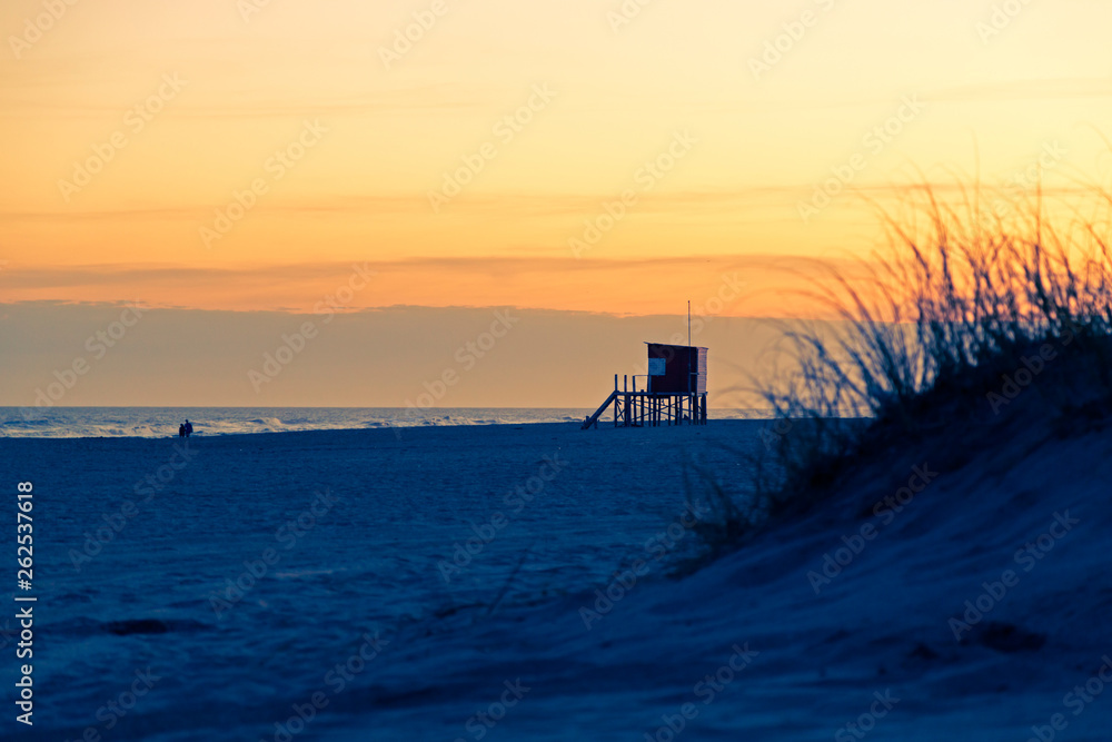MAR DE LAS PAMPAS. ARGENTINA. Beautiful view of the beach at the sunset. The Lifeguard tower, the sea,  sand, dunes, grass, and orange sky. The end of a the sunny day of summer in the atlantic coast.