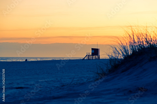 MAR DE LAS PAMPAS. ARGENTINA. Beautiful view of the beach at the sunset. The Lifeguard tower, the sea, sand, dunes, grass, and orange sky. The end of a the sunny day of summer in the atlantic coast.