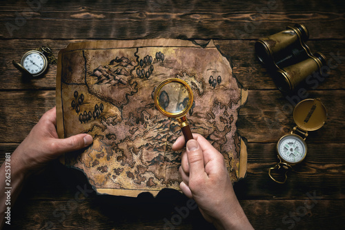 Картината върху платно Old map in man adventurer hands on a brown table background