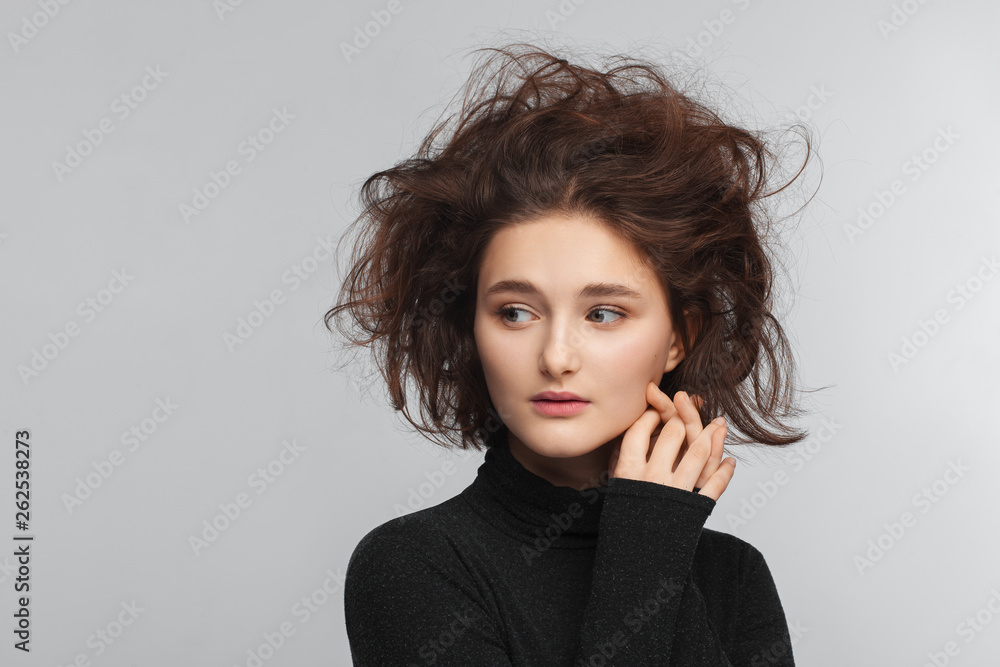 Portrait of a beautiful teen girl in a black sweater on a gray background. Combed up hair Portrait of a beautiful teen girl in a black sweater on a gray background. Combed up hair
