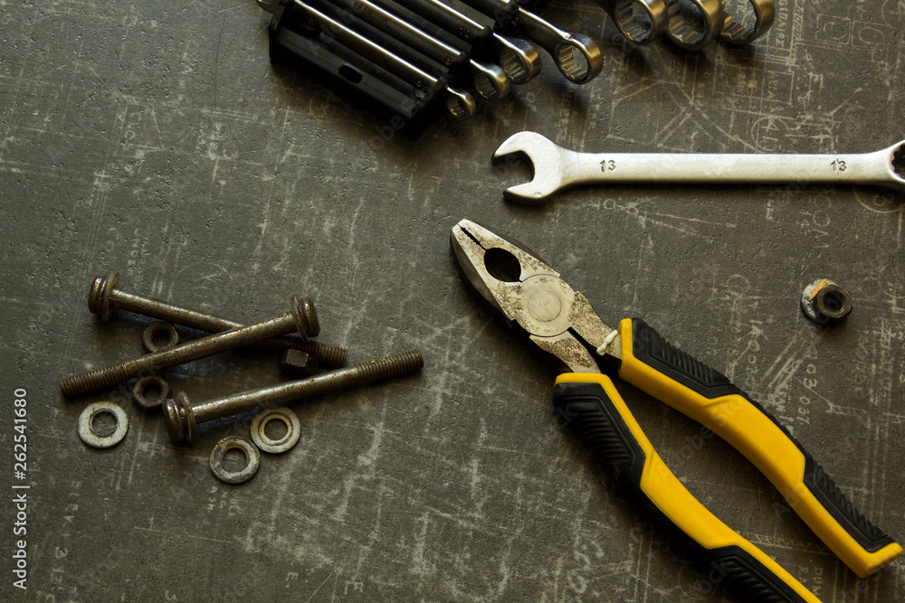 Tool set of pliers, wrenches, bolts and nuts on abstract grey surface Tool set of pliers, wrenches, bolts and nuts on abstract grey surface
