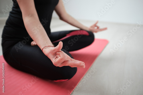 Close up of woman sitting on the mat in lotus posture.