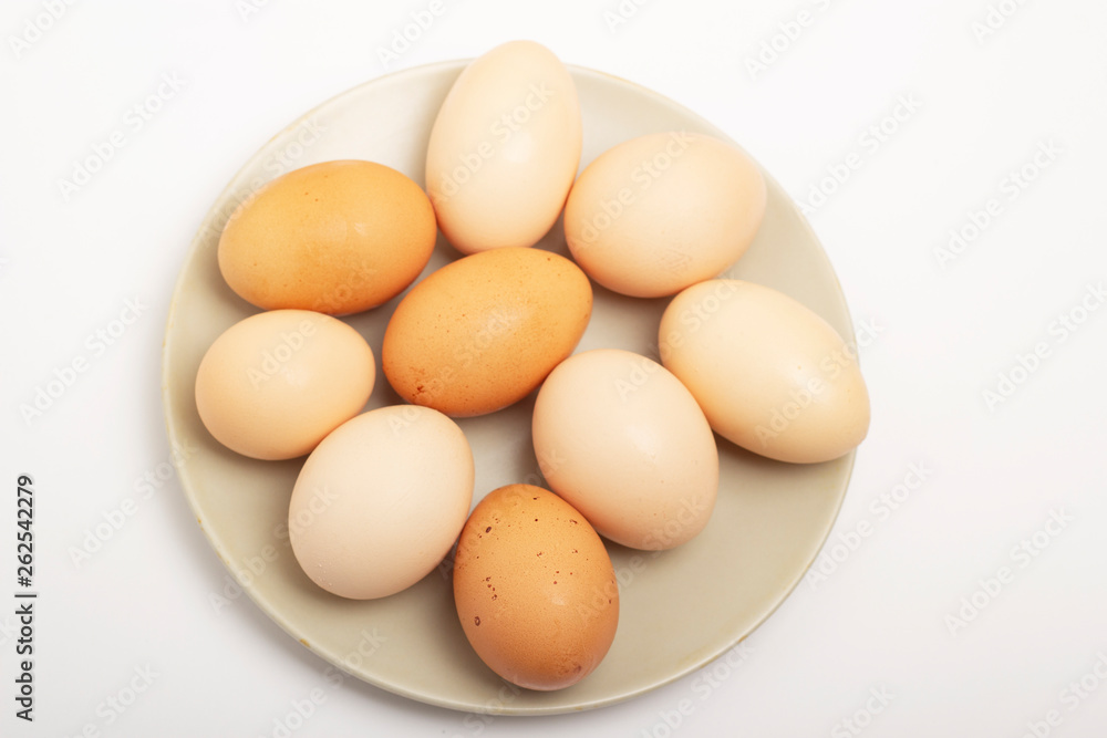 Nine brown raw eggs lie on a gray plate on a white background Nine brown raw eggs lie on a gray plate on a white background