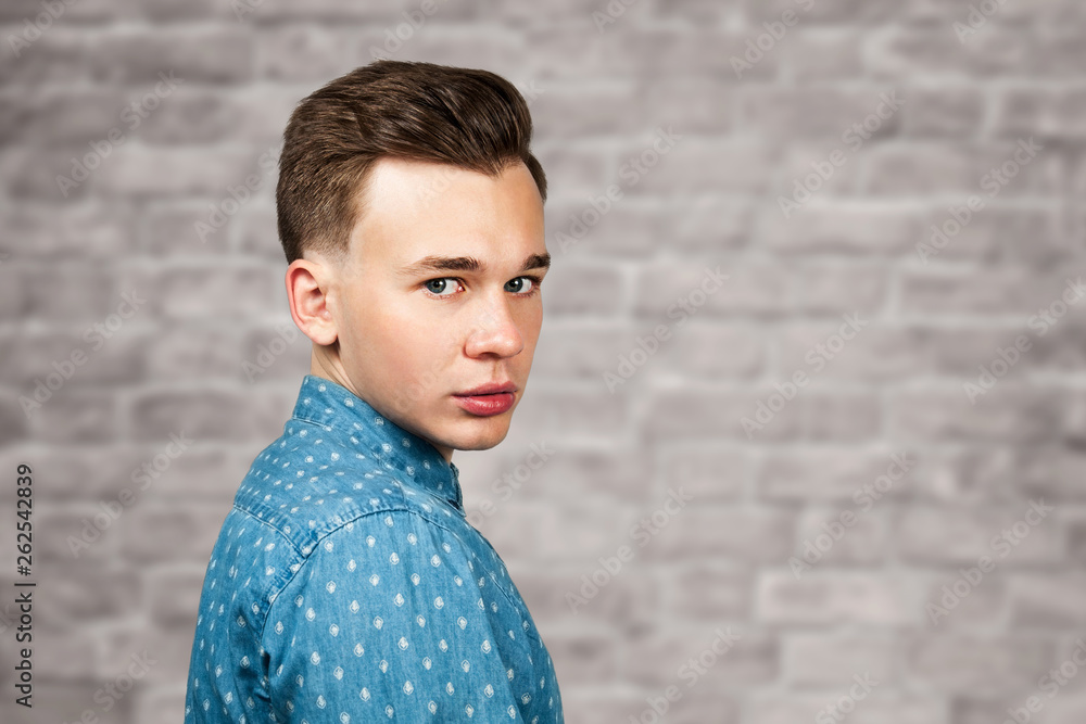 portrait white young guy model dressed in blue shirt looking at the camera on brick wall background portrait white young guy model dressed in blue shirt looking at the camera on brick wall background