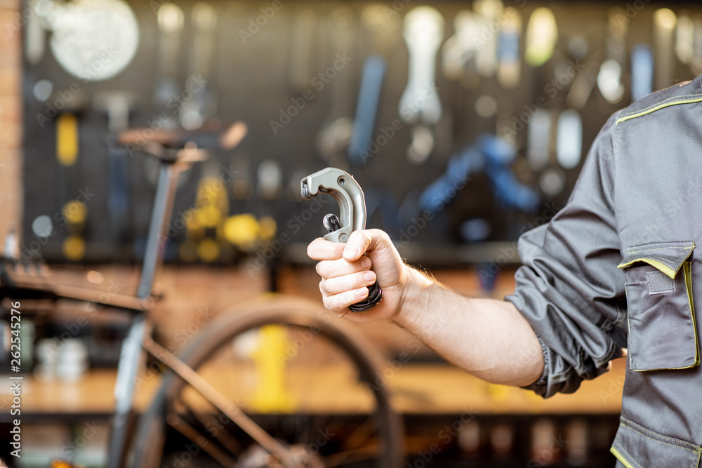Repairman holding tube cutter for bicycle helm in the workshop, close-up view Repairman holding tube cutter for bicycle helm in the workshop, close-up view