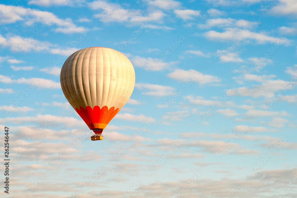 Naklejka premium Hot air balloon in blue cloudy sky