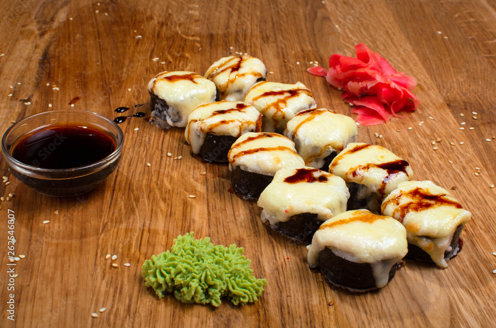 Unusual sushi rolls on a wooden table. Ukrainian sushi rolls with baked cheese and crabs Unusual sushi rolls on a wooden table. Ukrainian sushi rolls with baked cheese and crabs