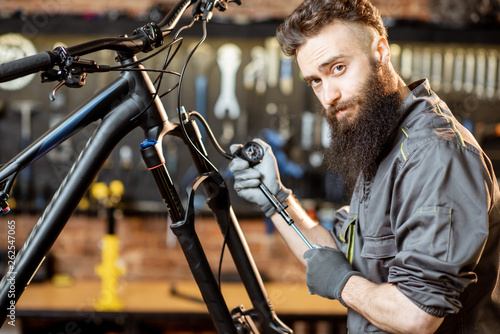 Repairman pumping shock absorber of the mountain bike in the workshop of the bicycle shop