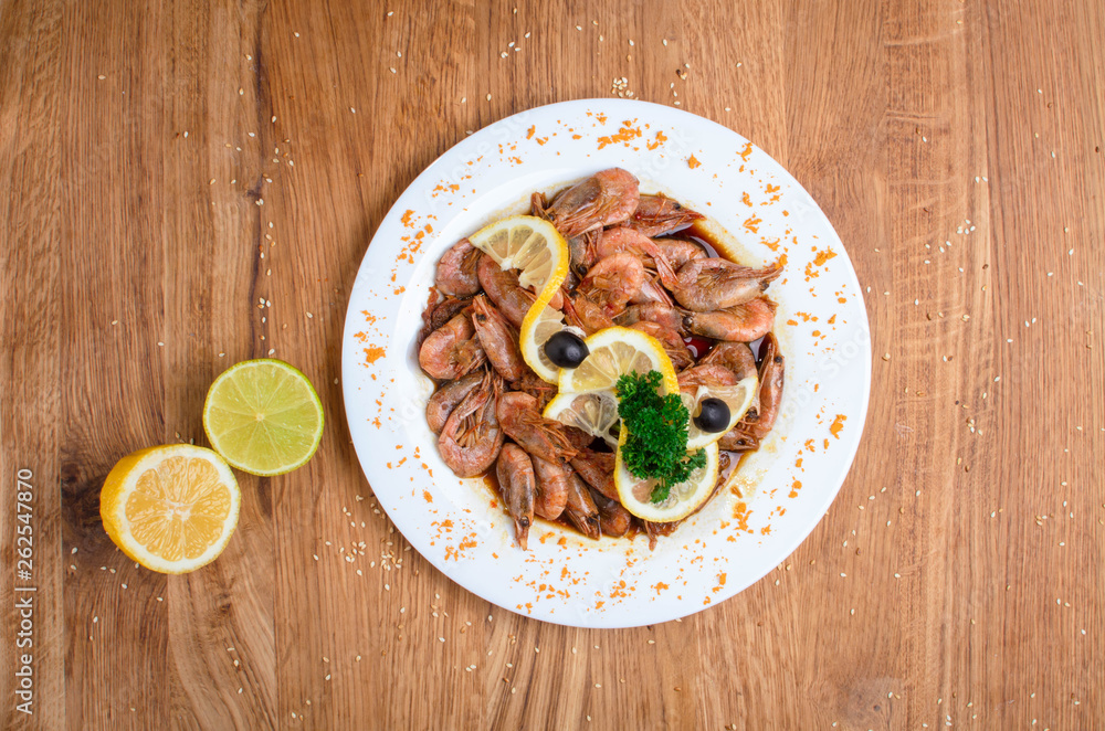 Appetizing shrimps in soy sauce on a white dish. Shrimps with olives and lemon. Restaurant seafood dish. Tasty diet food Appetizing shrimps in soy sauce on a white dish. Shrimps with olives and lemon. Restaurant seafood dish. Tasty diet food