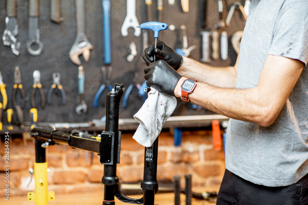 Man disassembling shock absorber of a bicycle fork at the workshop, close-up view Man disassembling shock absorber of a bicycle fork at the workshop, close-up view