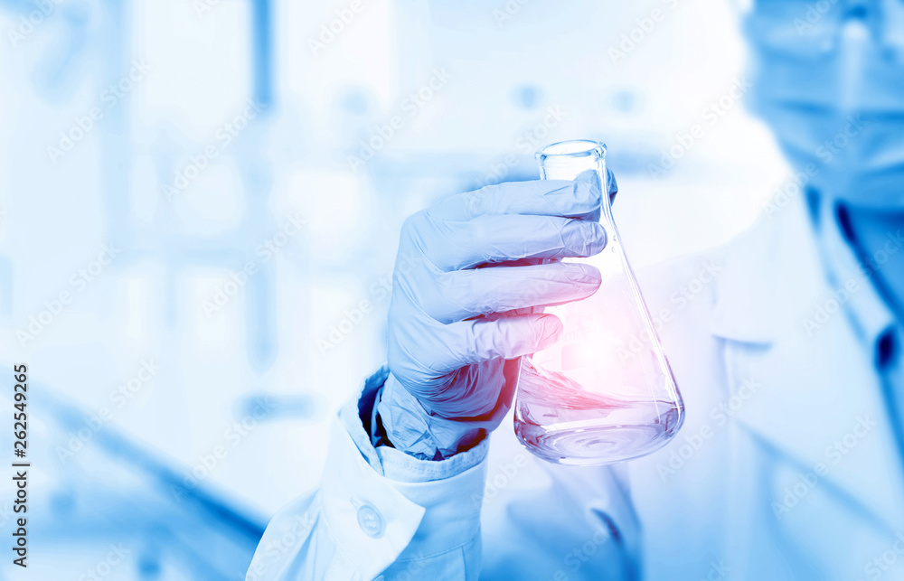 Laboratory beaker in analyst's hand in plastic glove Laboratory beaker in analyst's hand in plastic glove