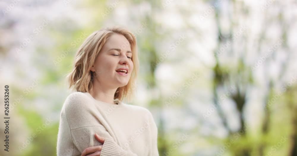 White female in cozy sweater outdoors in sunny green surroundings White female in cozy sweater outdoors in sunny green surroundings
