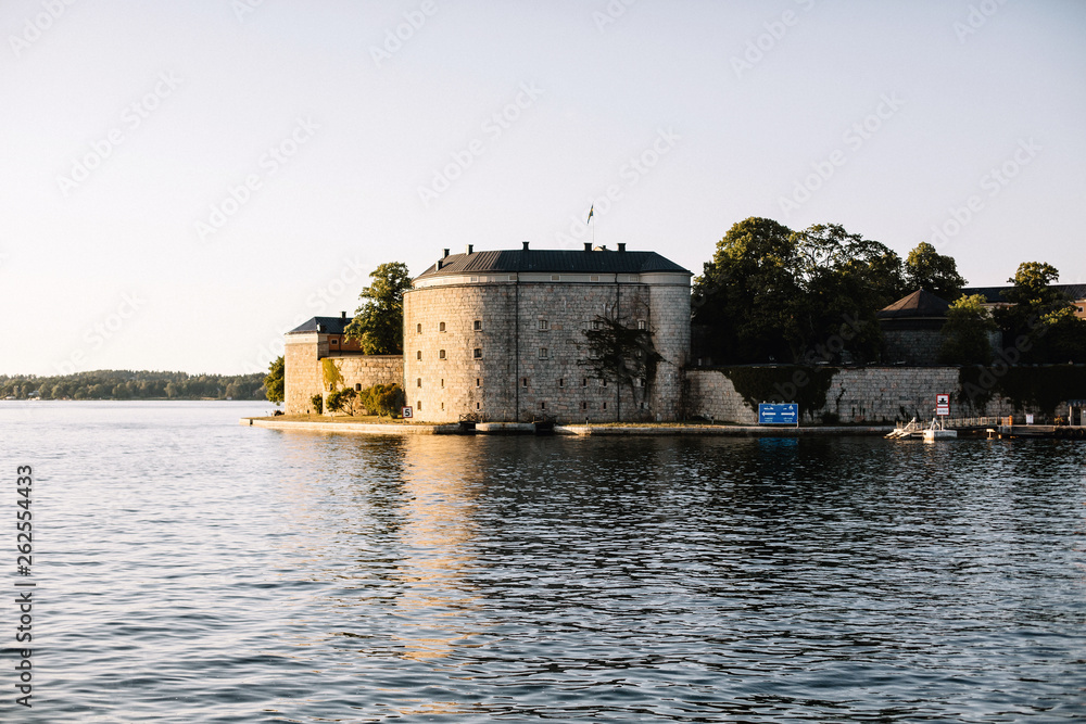 Exterior of Vaxholm fortress museum viewed from a sunset cruise sailing through an archipelago, in Stockholm, Sweden. 