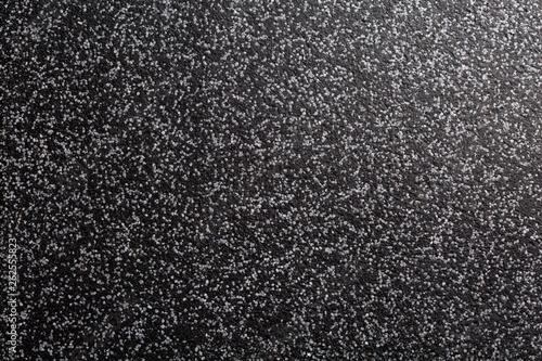 Close up of decorative quartz sand epoxy coated floor or wall coating with grey and black coloured particles. Side lighted