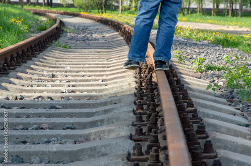 carefree teen walks along the railway rails, balances, amuses himself