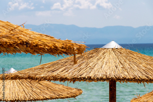 Straw beach umbrellas partial view against the Aegean Sea at Ammolofoi Beach, Kavala Region, Northern Greece