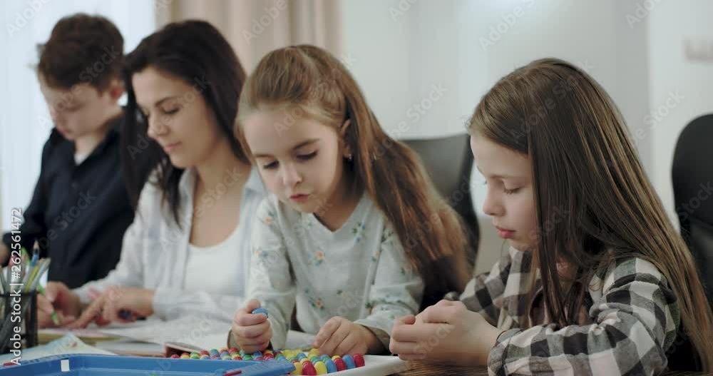 Closeup mother with her kids spending time together they drawing and playing a table game in the living room , very lovely atmosphere Closeup mother with her kids spending time together they drawing and playing a table game in the living room , very lovely atmosphere